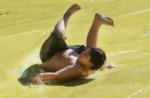 Payton Shirley, 9, of Medford rolls downs a slip-n-slide Saturday at Bear Creek Park.